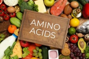 BCAAs vs. EAAs: Wooden board with text AMINO ACIDS among different products, top view